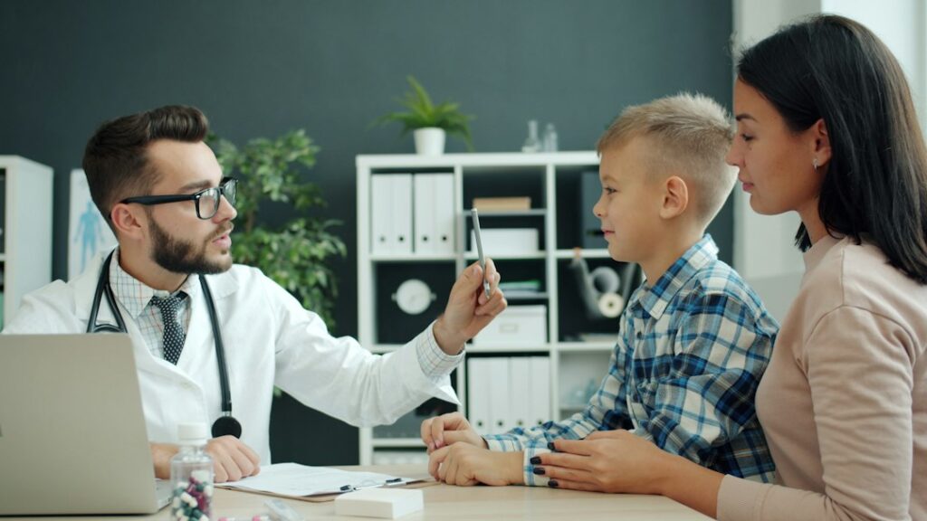 Doctor speaking with a parent and child in a clinic, illustrating preventive healthcare; not a documented vaccination event in Albania or Armenia.
