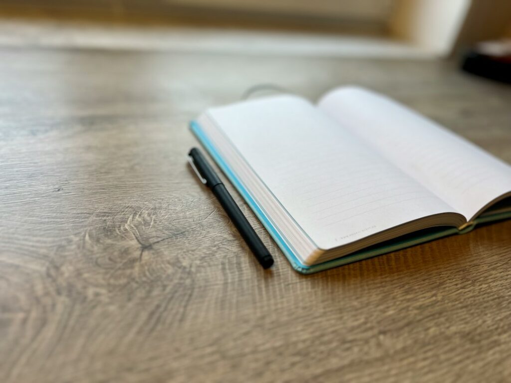 An open book and pen representing the documentation of language and stories; illustrative image, not from the Ojibwe project.
