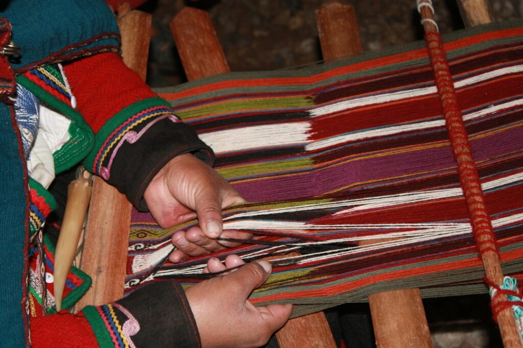 An artisan weaving colourful fabric on a loom, illustrating textile craftsmanship; not a photograph from the Living Heritage Days event in Georgia.
